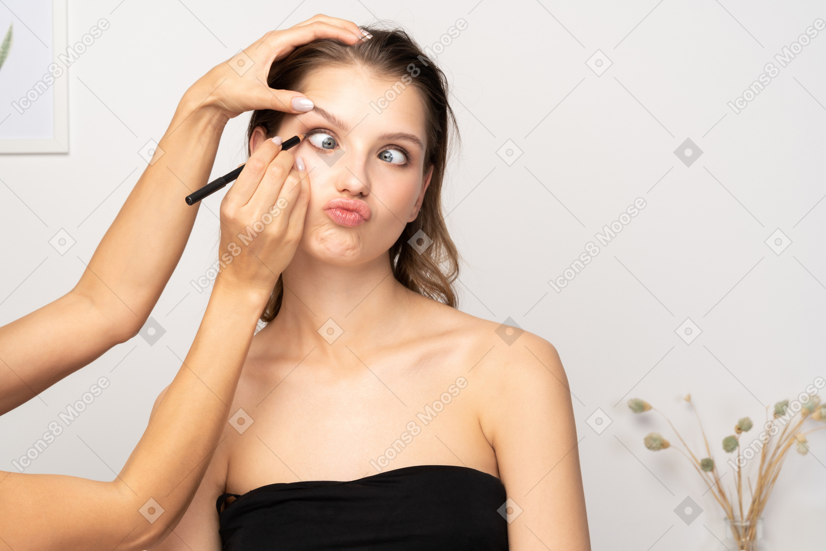 Front view of a make-up artist doing eye make-up for a crazy female model