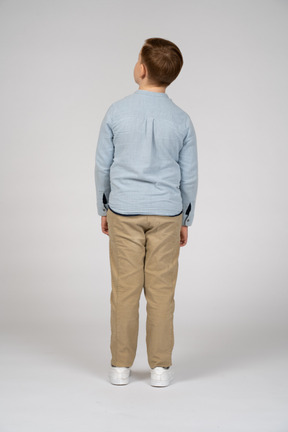 Vista trasera de un niño con ropa informal mirando hacia arriba