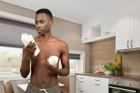 Shirtless man checking milk expiration date