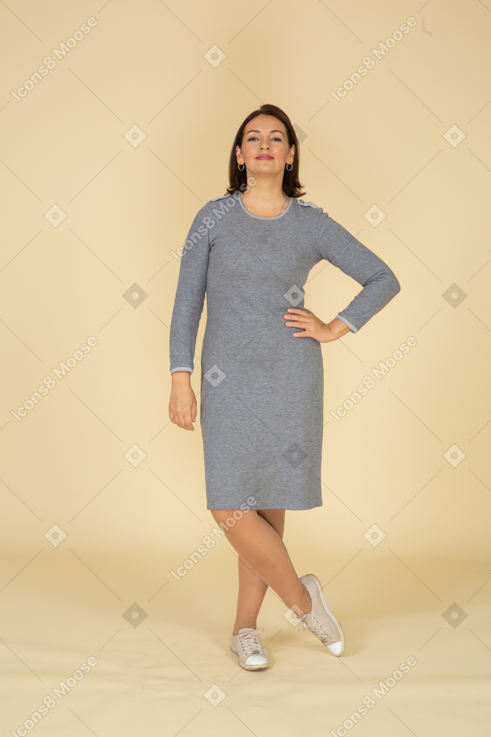 一个穿着灰色裙子摆姿势的快乐女人的前视图