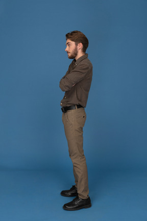 Slim young man standing with his arms crossed