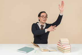 Joven estudiante asiática en un suéter levantando su mano