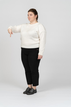 Plump woman in white sweater pointing down with a finger