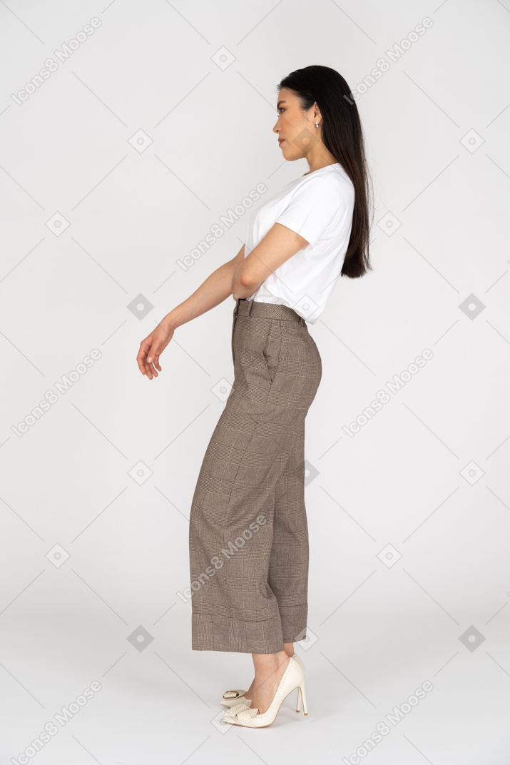 Side view of a thoughtful young woman in breeches putting hand on stomach