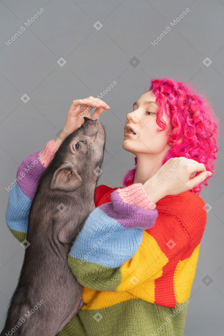 A young female playing wit a tiny pet pig