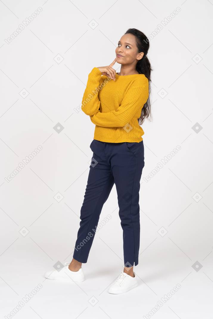 Vista frontal de uma garota pensativa em roupas casuais, olhando para cima e tocando o queixo com o dedo