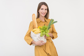 Mujer joven con bolsa de compras reusabel con verduras