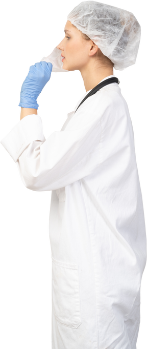 Vista lateral de uma jovem médica colocando uma máscara