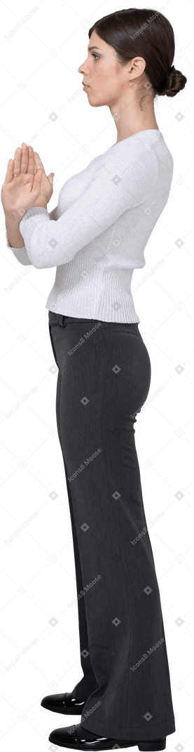 Vista lateral de una mujer joven en ropa de oficina cruzando los brazos
