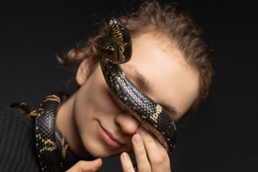 Pequeña serpiente arrastrándose sobre la frente de una mujer joven