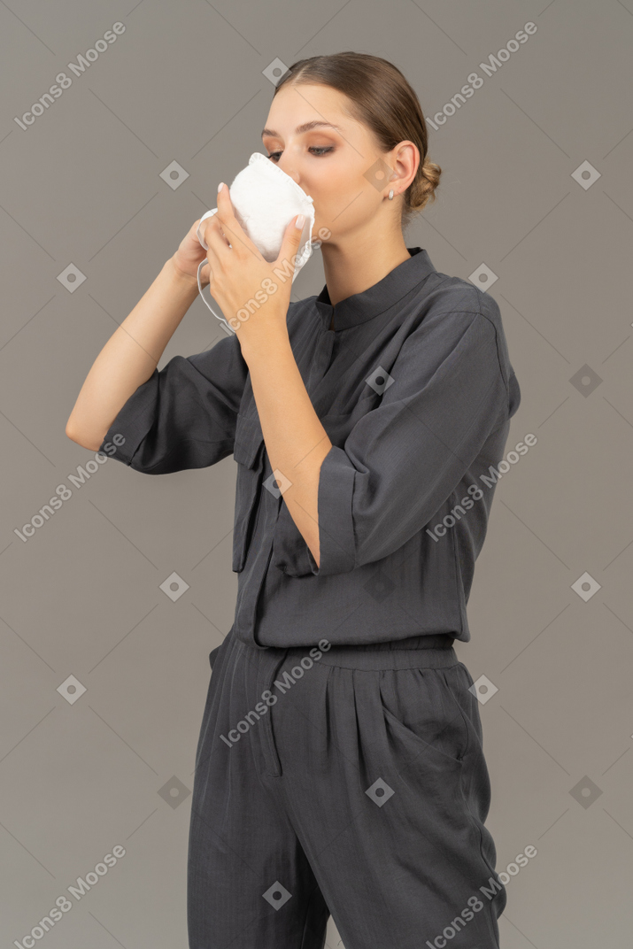 Frau in grauem overall, die eine atemschutzmaske anlegt