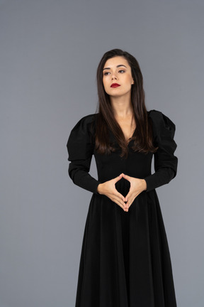 Vue de face d'une jeune femme autoritaire dans une robe noire, main dans la main