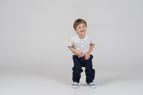 Front view of a boy squatting down a bit and smiling