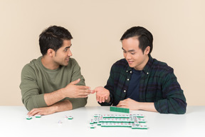 Young interracial friends sitting at the table and playing scramble game