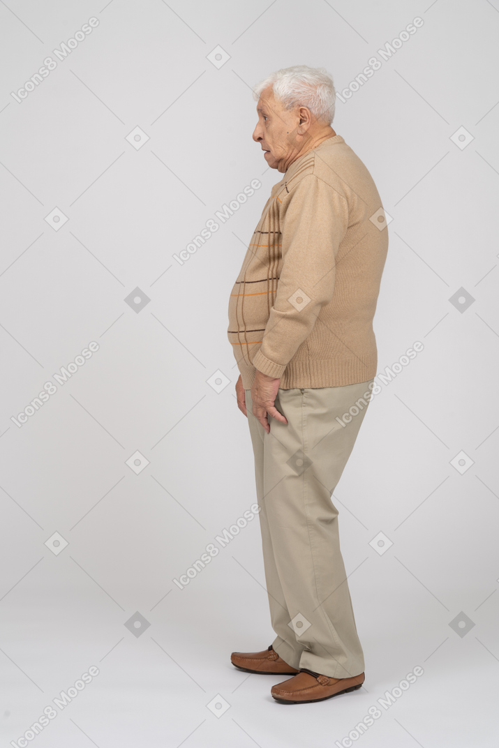 Вид сбоку на старика в повседневной одежде, стоящего на месте
