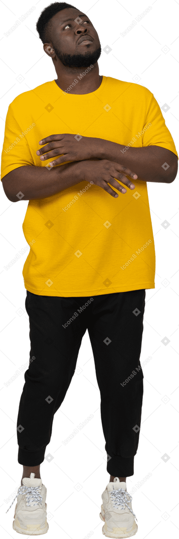 Front view of a young dark-skinned man in yellow t-shirt raising hands