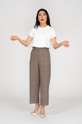 Front view of a shocked gesticulating young lady in breeches outspreading her hands
