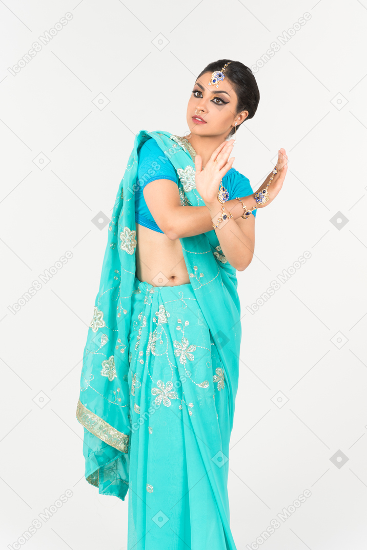 Junge indische frau im blauen sari, der in tanzposition steht