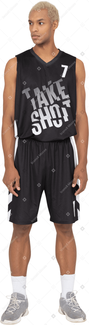 Vista frontale di un giovane giocatore di basket maschile in piedi immobile e guardando da parte