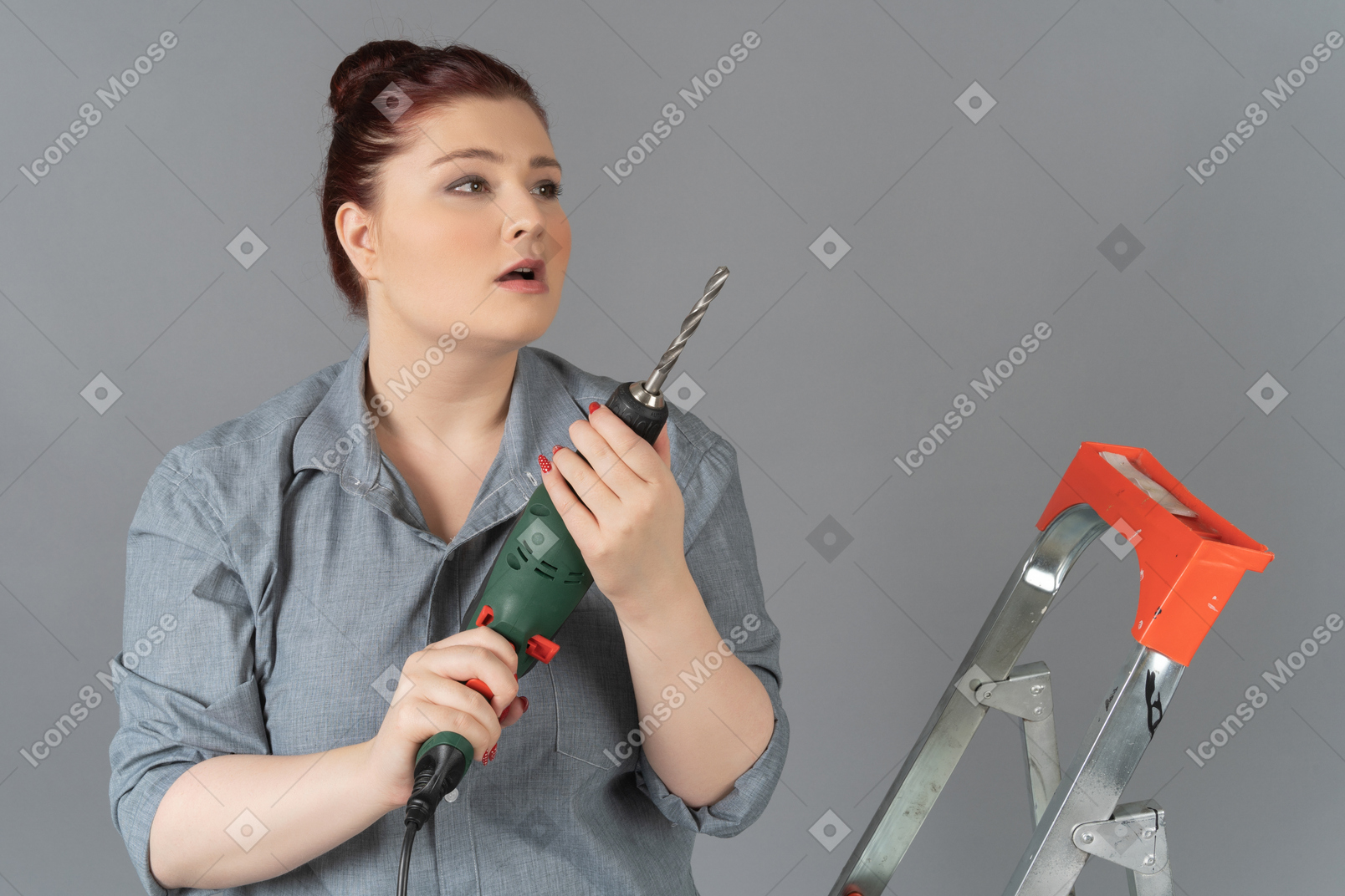 Young woman looking surprisingly sideways and holding a drill