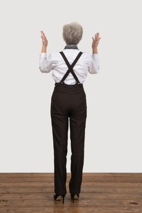 Back view of an old lady in office clothing raising her hands