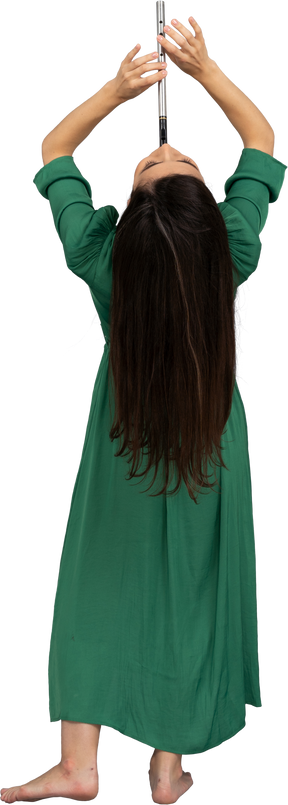Vista de trás de uma jovem de vestido verde tocando flauta enquanto se inclina para trás