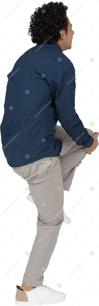 Vista lateral de un hombre en ropa casual tocando su rodilla lastimada
