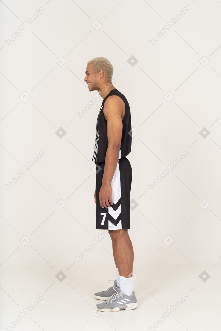 여전히 서있는 웃고있는 젊은 남자 농구 선수의 측면보기