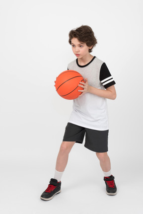 El chico se ve concentrado y listo para lanzar una pelota de baloncesto.