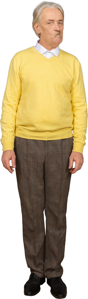 Vista frontal de un anciano sospechoso en un jersey amarillo mirando a la cámara