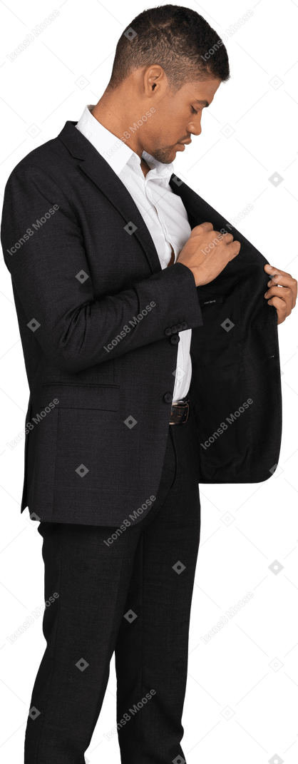 Вид сбоку на молодого человека в черном костюме, кладущего что-то в карман