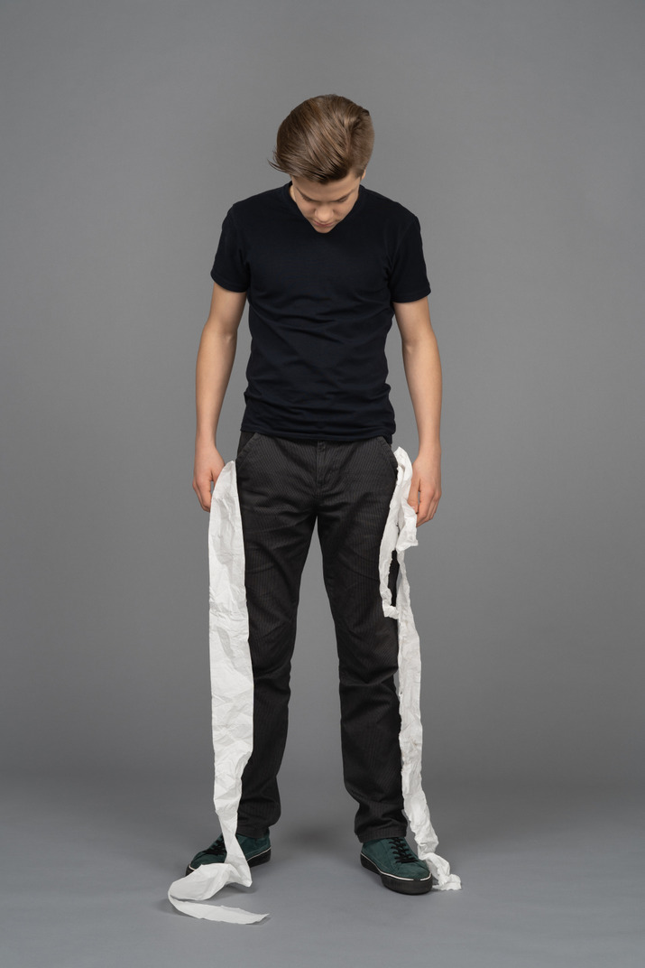 Male model looking down toilet paper rolling out of his pockets