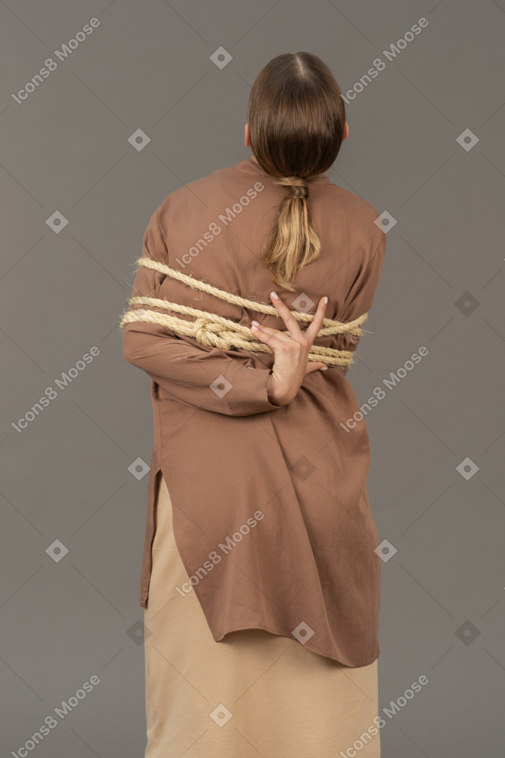 一个被捆绑的女人伸手去拿绳子的背影