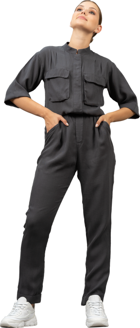 Front view of a proud young woman in a jumpsuit putting hands on hips
