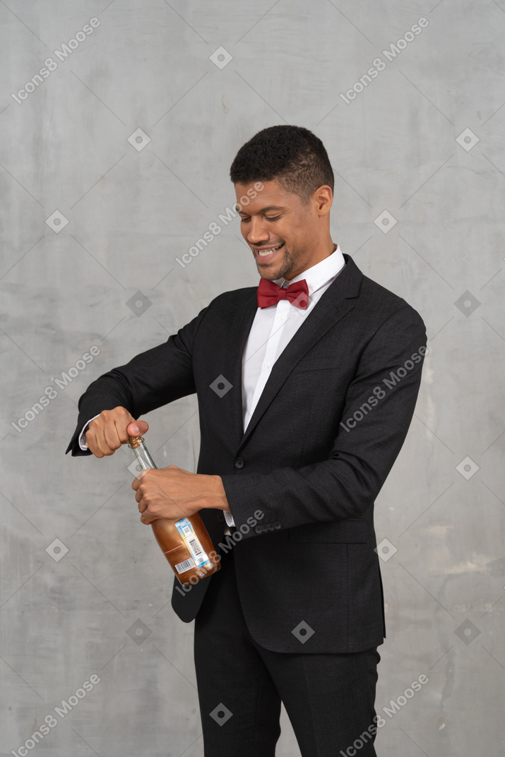 Uomo sorridente in giacca e cravatta che apre una bottiglia di champagne