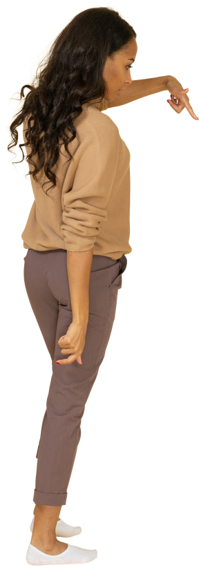 Vista posterior de tres cuartos de una mujer joven de piel oscura que señala con el dedo hacia abajo