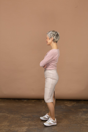 一个穿着休闲服的女人双臂交叉站立的侧视图