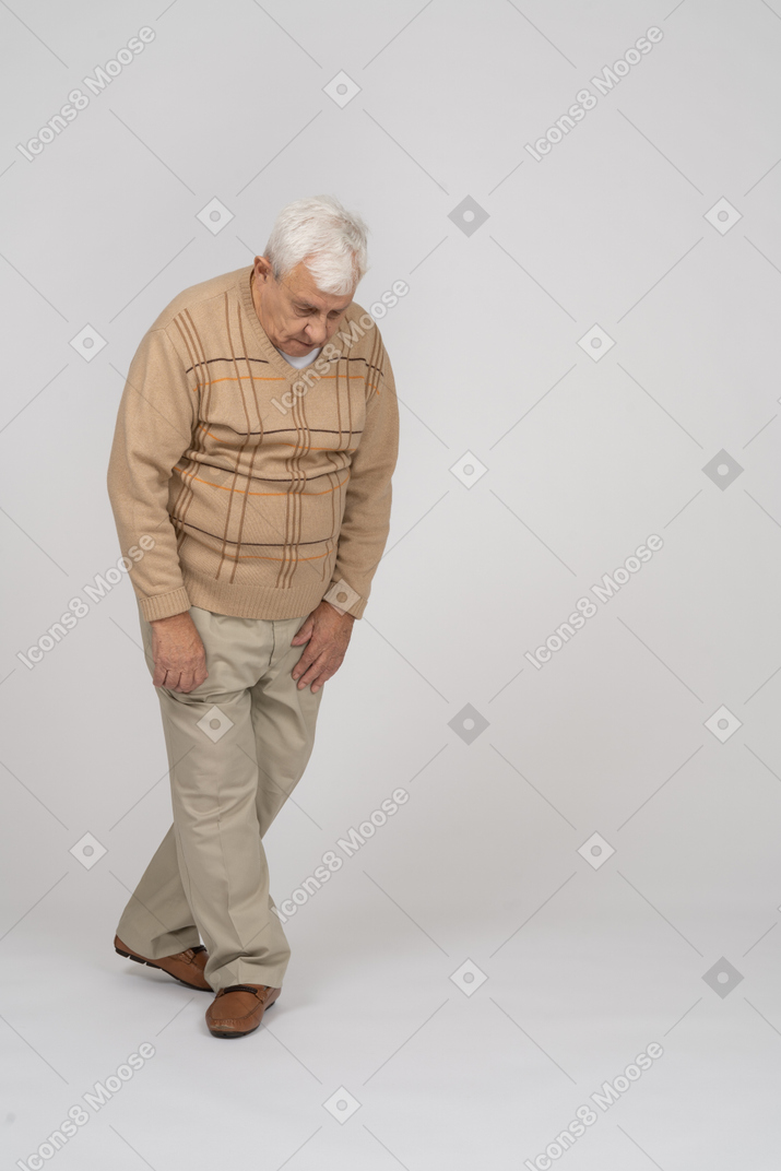 Vue de face d'un vieil homme en vêtements décontractés debout avec les jambes croisées