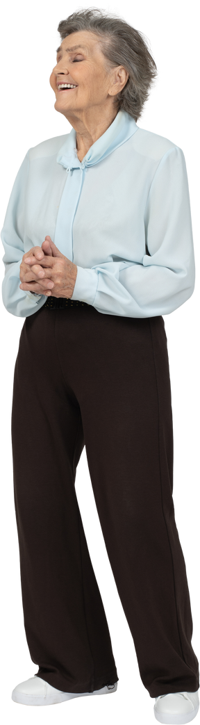 Vista frontal de una mujer mayor feliz en blusa y pantalones tomados de la mano juntos