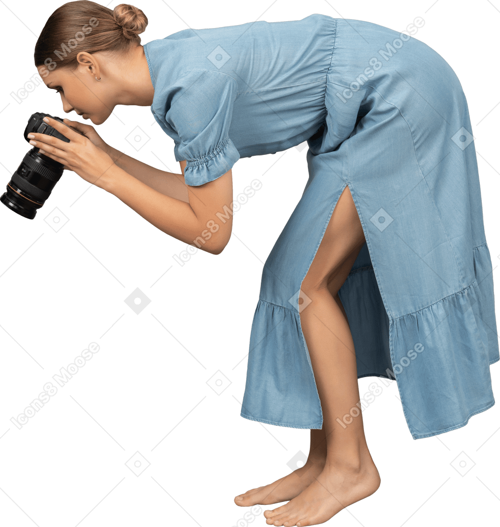 Vista lateral de uma jovem de vestido azul tirando uma foto
