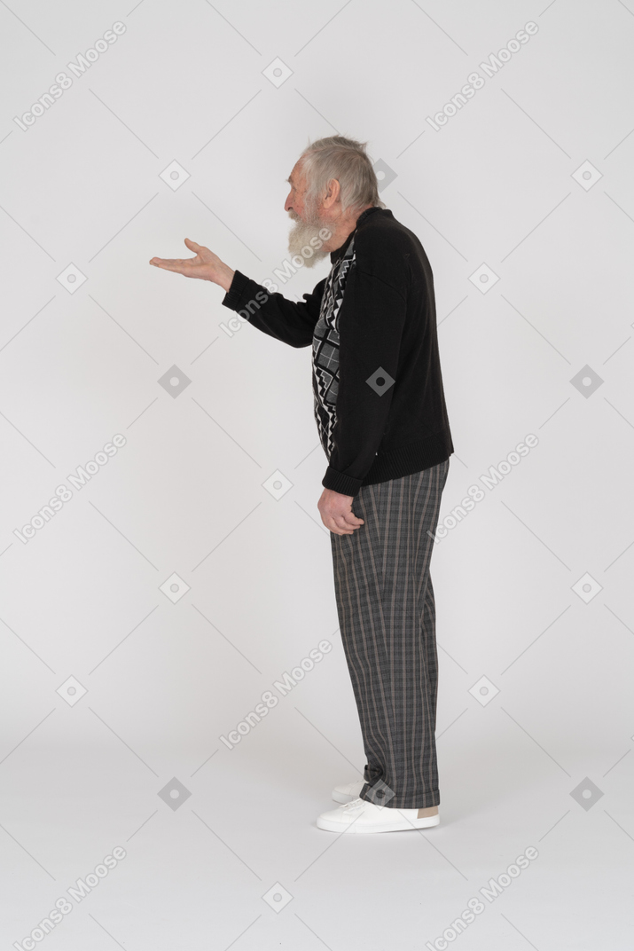 Side view of an old man standing and holding up his hand