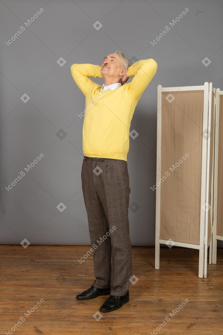 Vista de tres cuartos de un anciano descansando poniendo las manos detrás de la cabeza