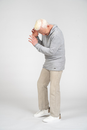 Hombre de mediana edad de pie y cubriendo su rostro