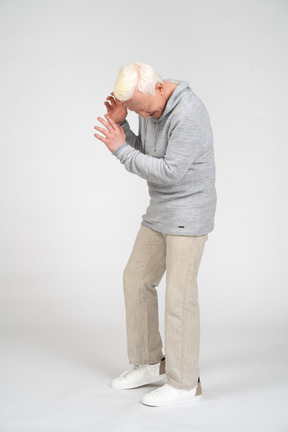 Middle-aged man standing and covering his face