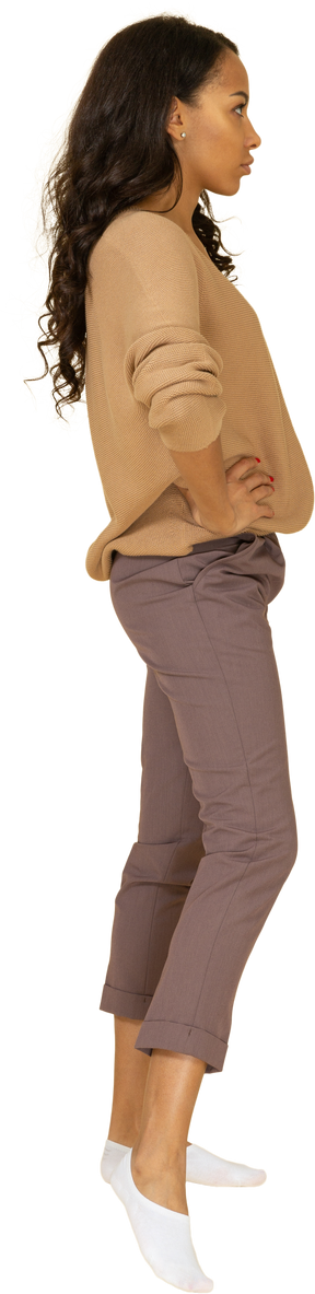 Vue latérale d'une jeune femme à la peau foncée mettant les mains sur les hanches