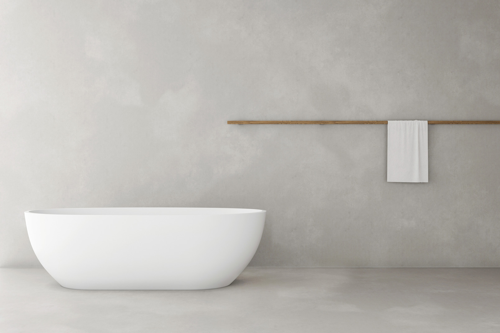 A minimalistic bathroom with a single-standing white oval bathtub and a single white towel on the wall