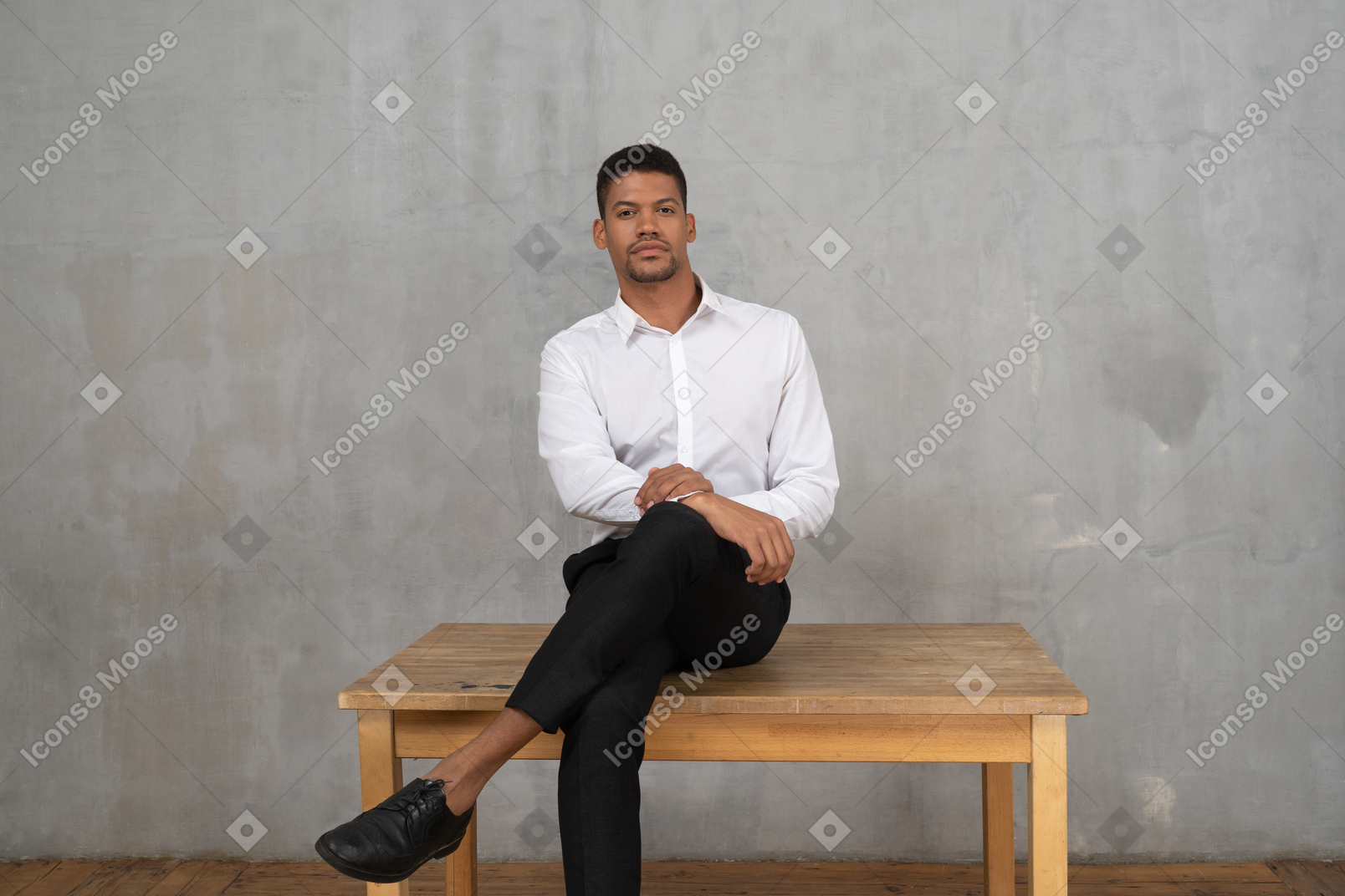 Confident man in formal clothes sitting cross legged on a table