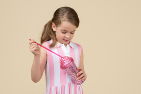 Linda niña sosteniendo un vaso de plástico con una pajita