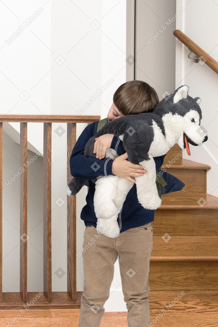 A little boy hugging a husky stuffed animal