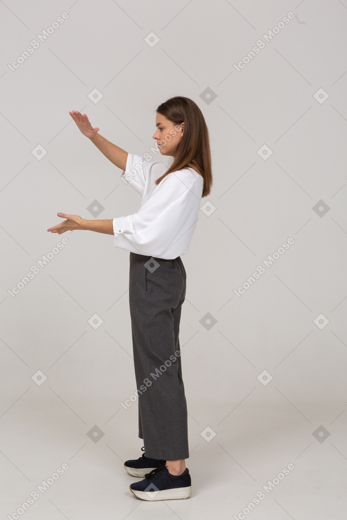Vue latérale d'une jeune femme en vêtements de bureau montrant une taille de quelque chose